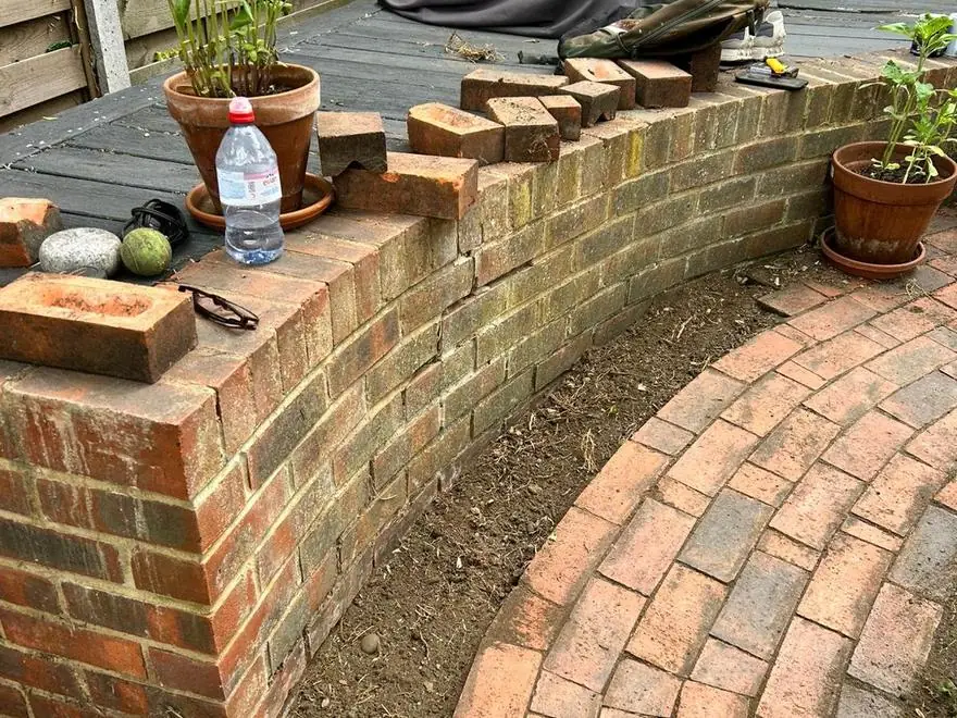 The rebuilt brick wall and relaid curved path, planted up
